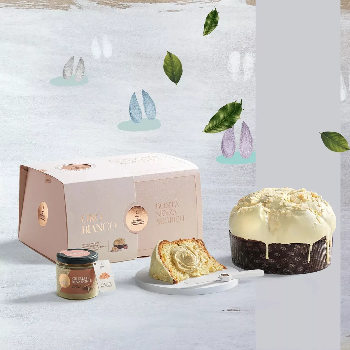 Panettone Fiasconaro Oro Bianco avec sa couverture de chocolat blanc, accompagné de sa crème aux amandes et de son élégant coffret rose pâle dans un décor poétique de feuillages