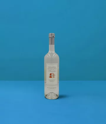Flasche Grappa Moscato Negroni (70cl) auf blauem Hintergrund, ein Spiegelbild der handwerklichen Destillation und der italienischen Qualität.