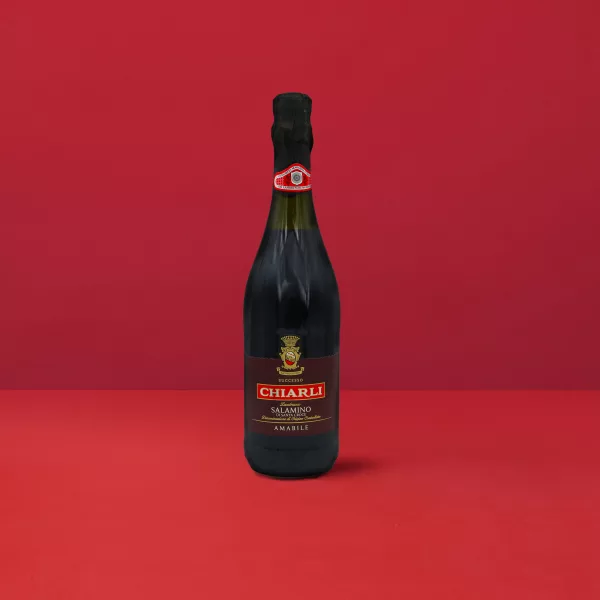 Bouteille de Lambrusco Classico Salamino - Chiarli DOC sur un fond rouge élégant.