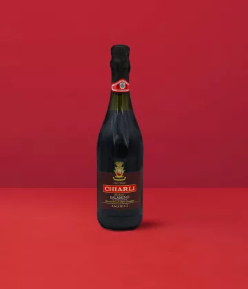 Flasche Lambrusco Classico Salamino - Chiarli DOC auf einem eleganten roten Hintergrund.