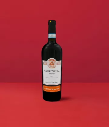 Flasche Nero d'Avola - Terre Normanne DOP, die das intensive Rot und die granatroten Reflexe widerspiegelt, die für den sizilianischen Wein charakteristisch sind.