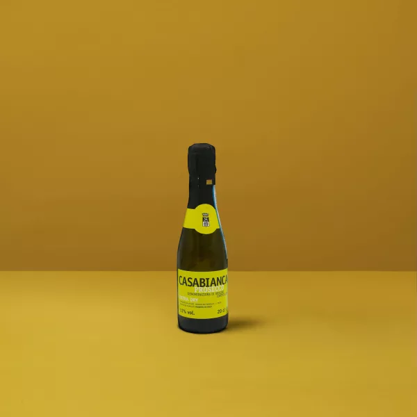 Una piccola bottiglia di Prosecchino Extra Dry Casabianca DOCG, dal colore giallo chiaro e dalle bollicine fini, perfetta per un brindisi festivo.