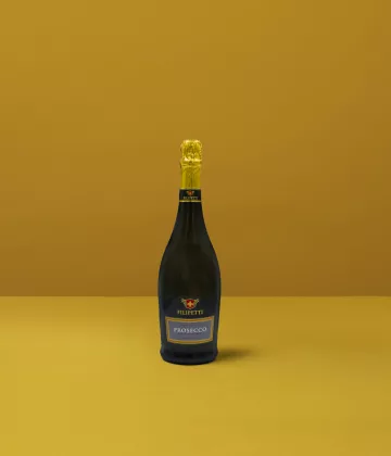 Una bottiglia di Prosecco Extra Dry Filipetti su sfondo giallo, simbolo di finezza e celebrazione italiana.