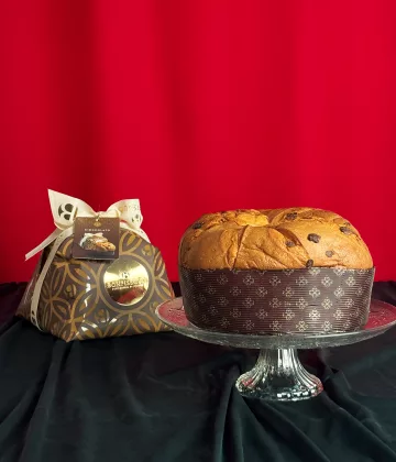 Panettone Chocolat Bonfissuto présenté sur un plat en cristal avec son coffret doré orné de motifs géométriques sur fond rouge festif