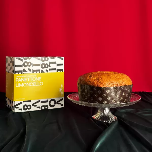Panettone Limoncello Olivieri präsentiert auf einer Kristallplatte mit seiner typografischen gelb-weißen Schachtel auf festlich rotem Hintergrund